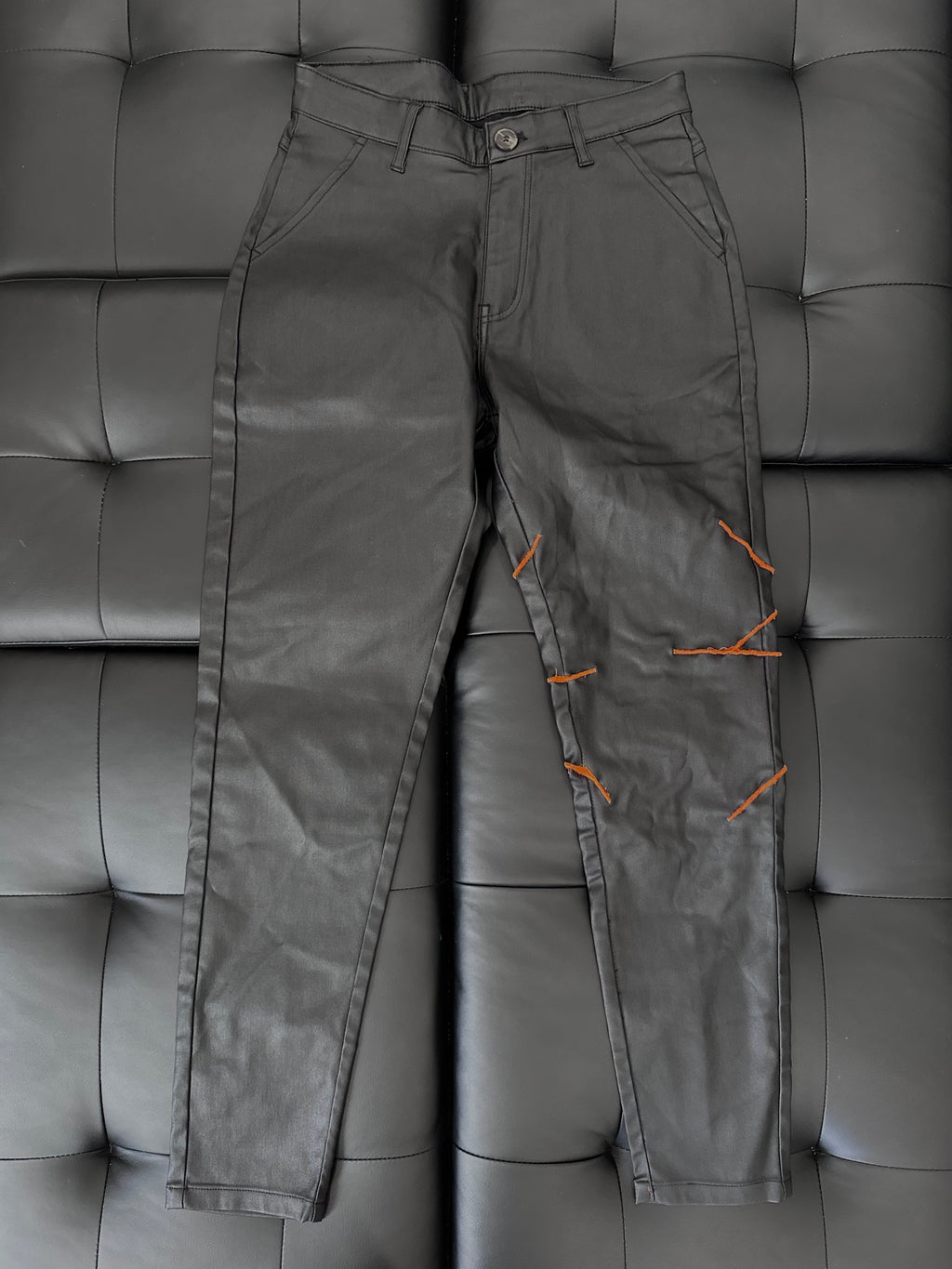 Faux leather pants with a neon orange embroidered web