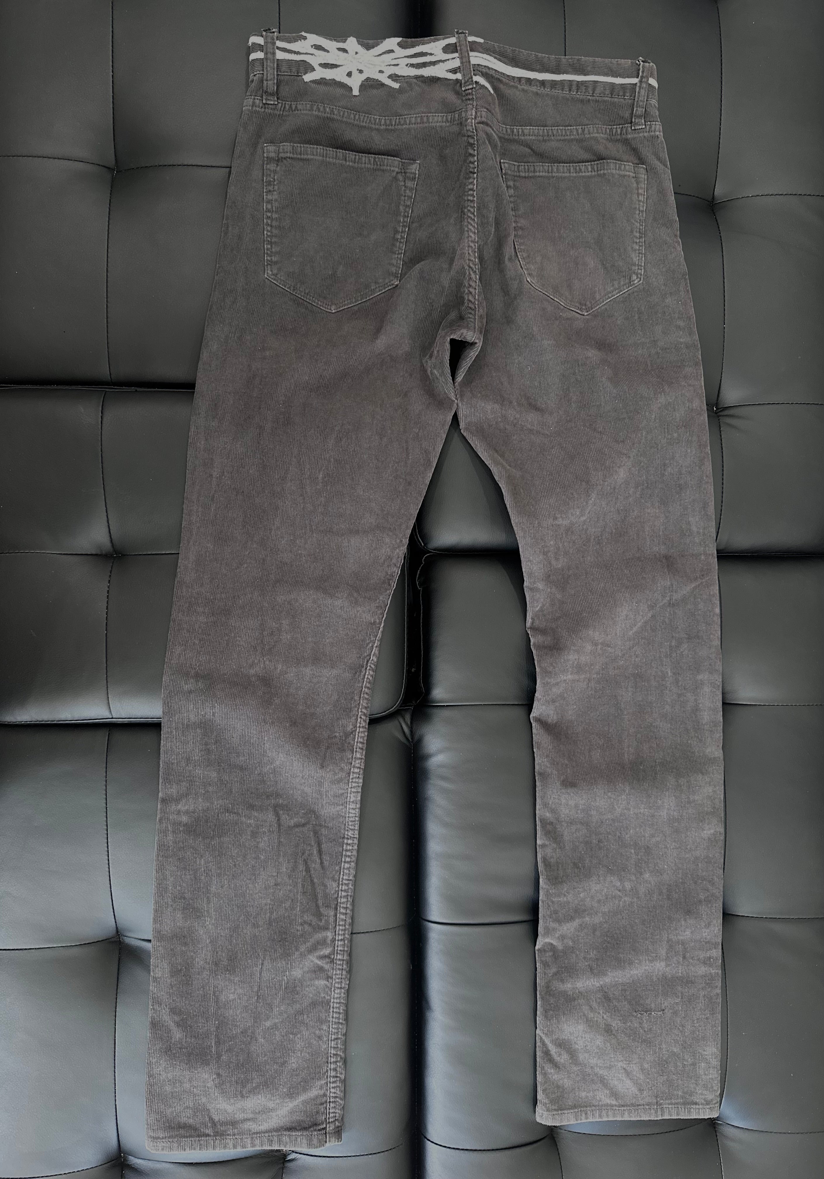 Grey corduroy pants with web embroidered around the waist