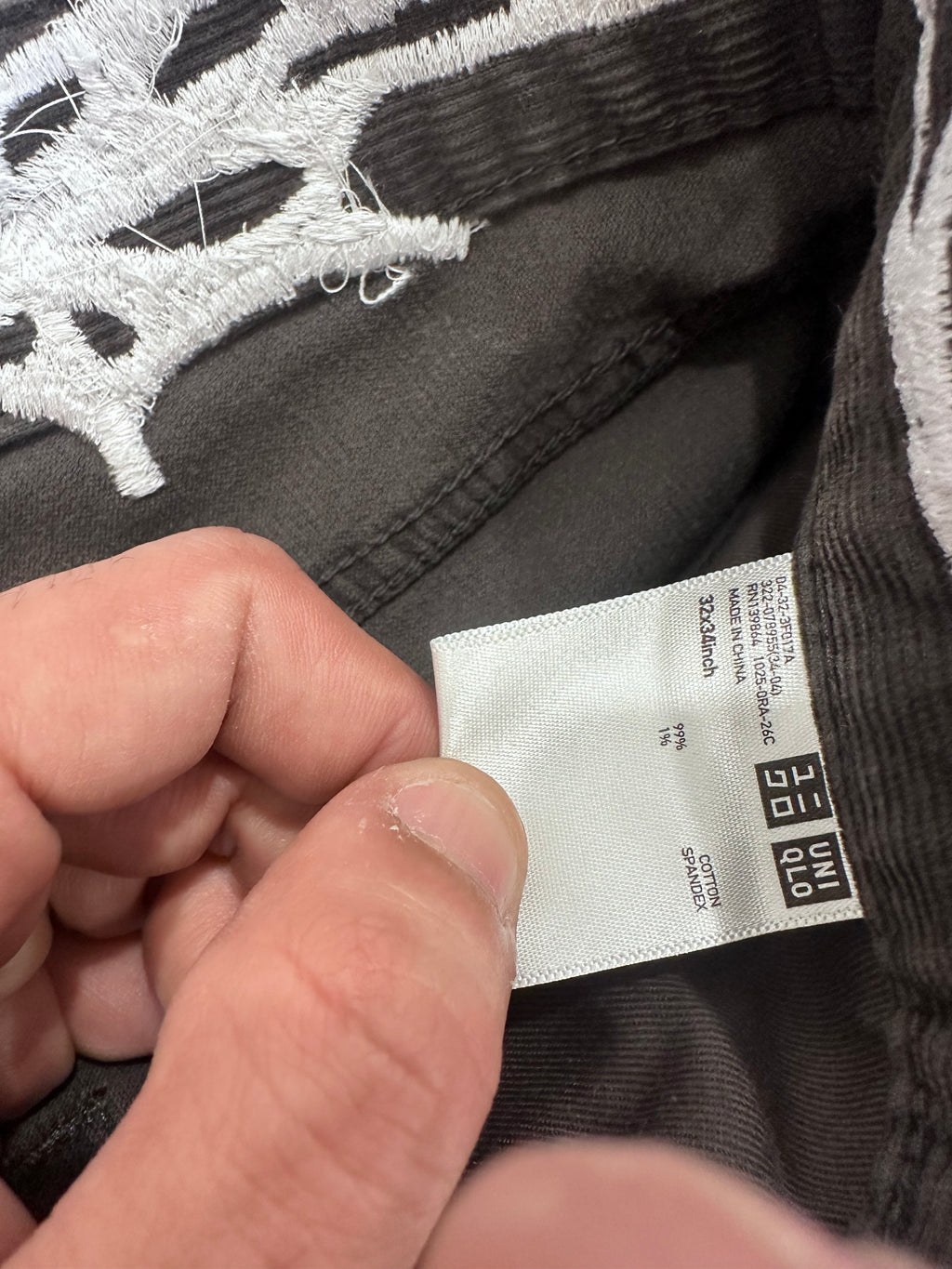 Grey corduroy pants with web embroidered around the waist