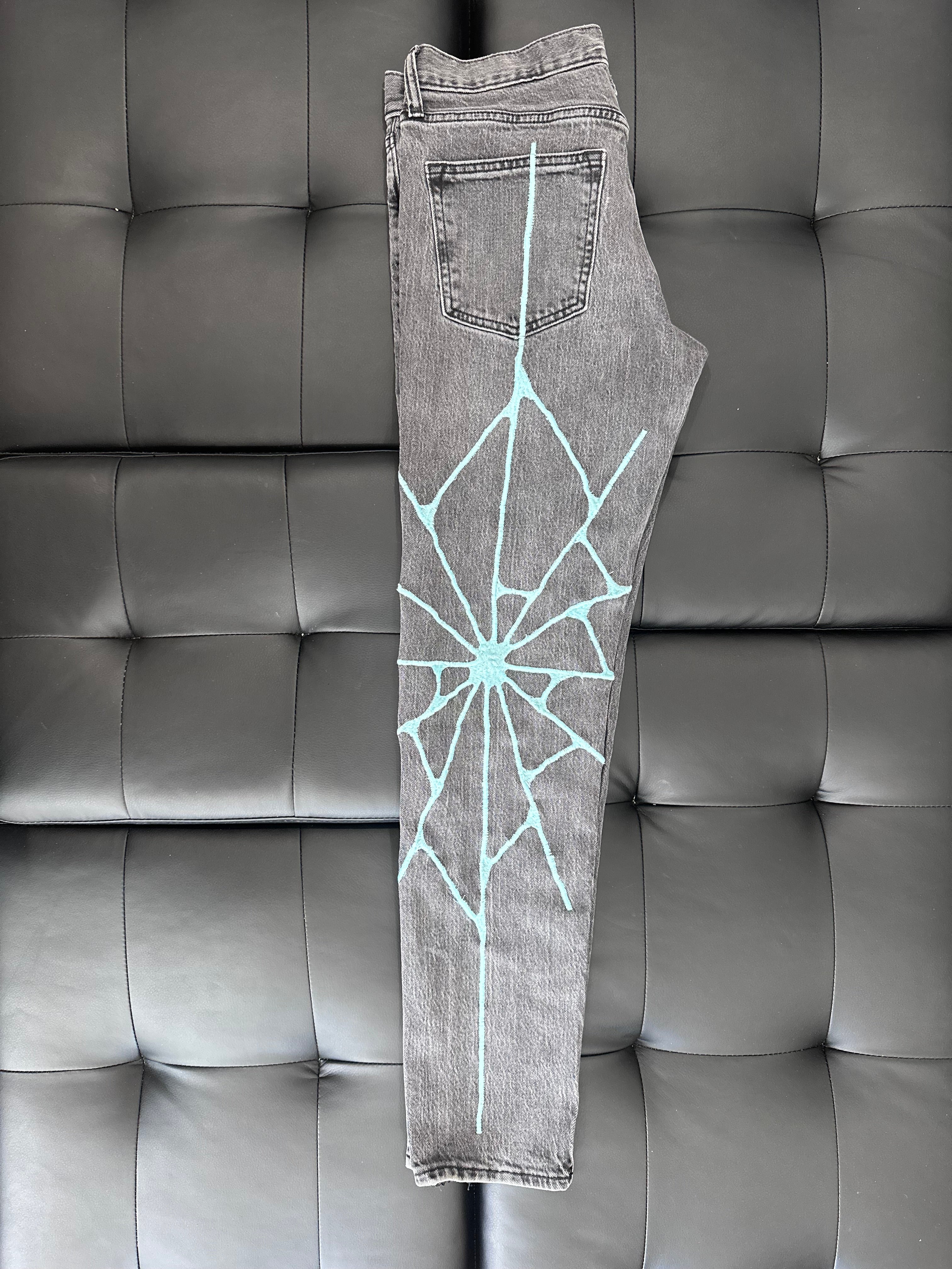 Grey slim taper jeans with a teal embroidered web