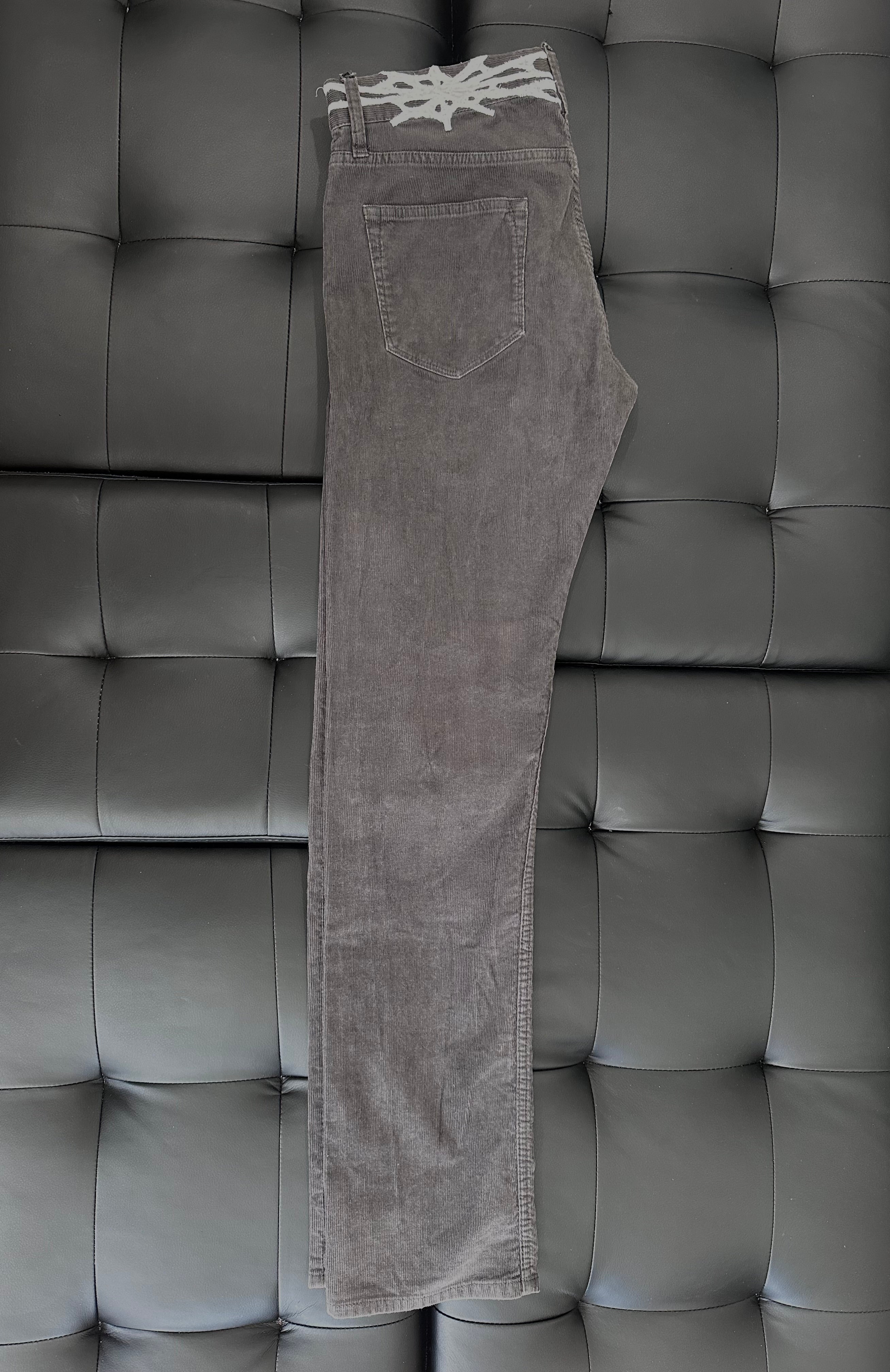 Grey corduroy pants with web embroidered around the waist